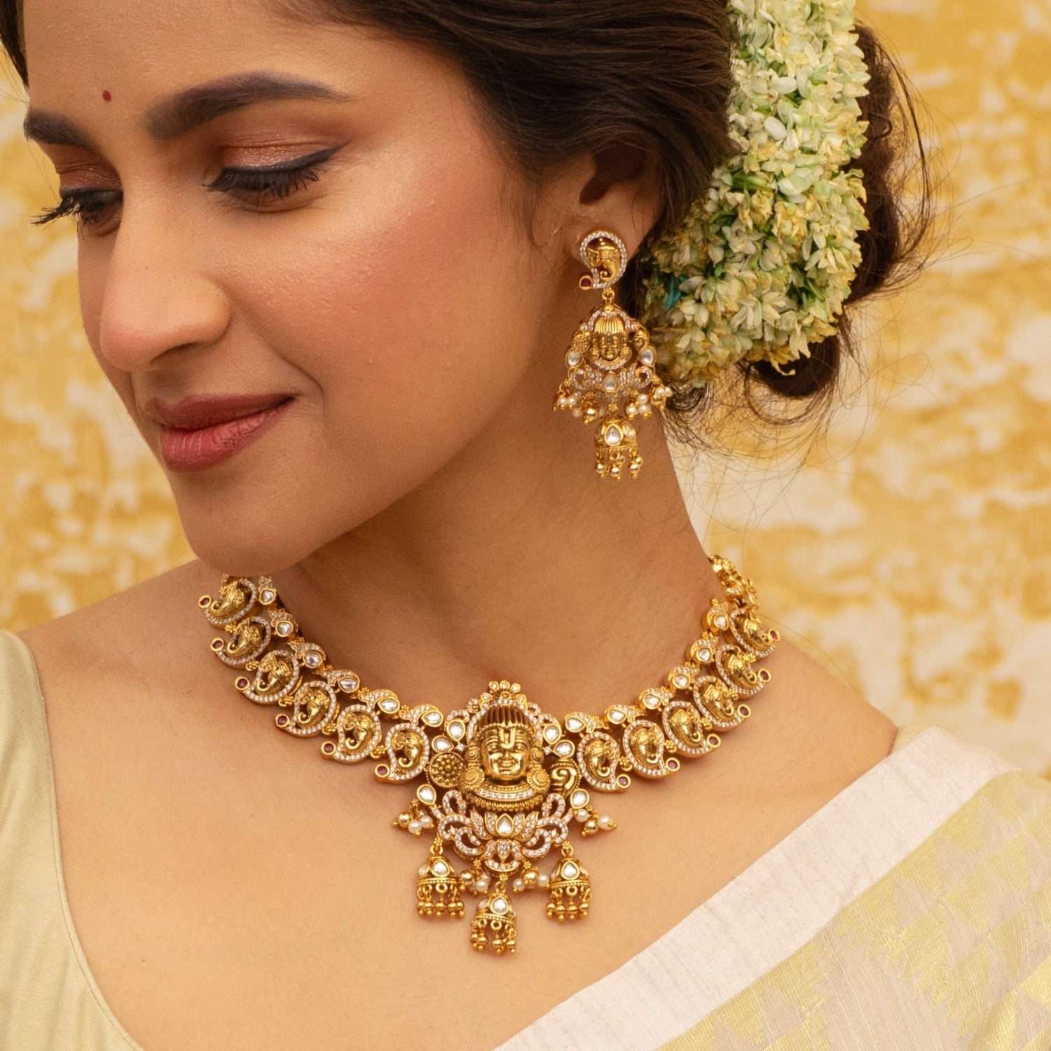 Close up image of a gold plated necklace with intricate designs and a Lord Balaji motif.